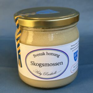 Glasburk med honung. Texten "Skogsmossen" står i en blålila oval.